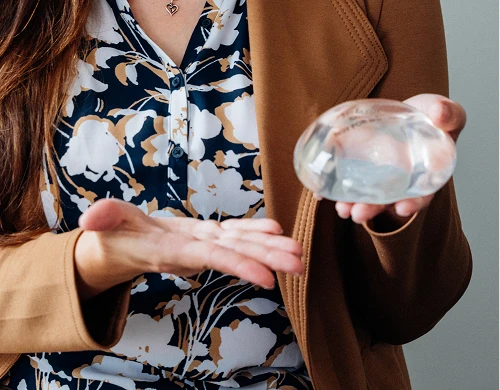 Two professionals exchanging business cards in close-up view, one wearing floral dress and tan blazer - Breast reconstruction in San Antonio, TX