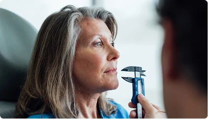 Doctor Stallworth MD examining mature woman's eye with diagnostic instrument during comprehensive consultation - Mohs in San Antonio, TX