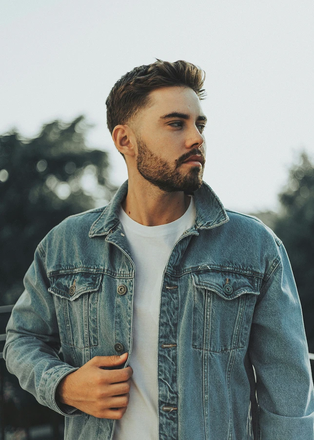 Bearded man in denim jacket and white shirt outdoors with natural background - Neograft in San Antonio, TX