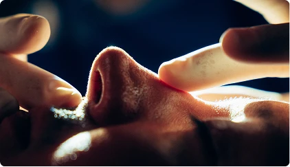Hands along the bridge of patients nose with strong dramatic lighting, close up - Rhinoplasty in San Antonio, TX