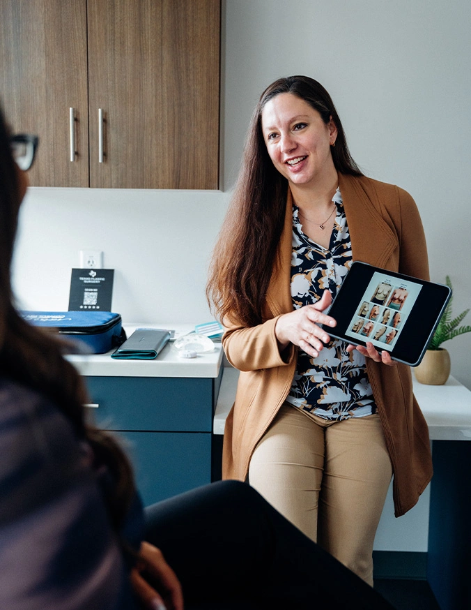 Professional woman presenting tablet device to clients in modern office setting during consultation - Breast augmentation in San Antonio, TX