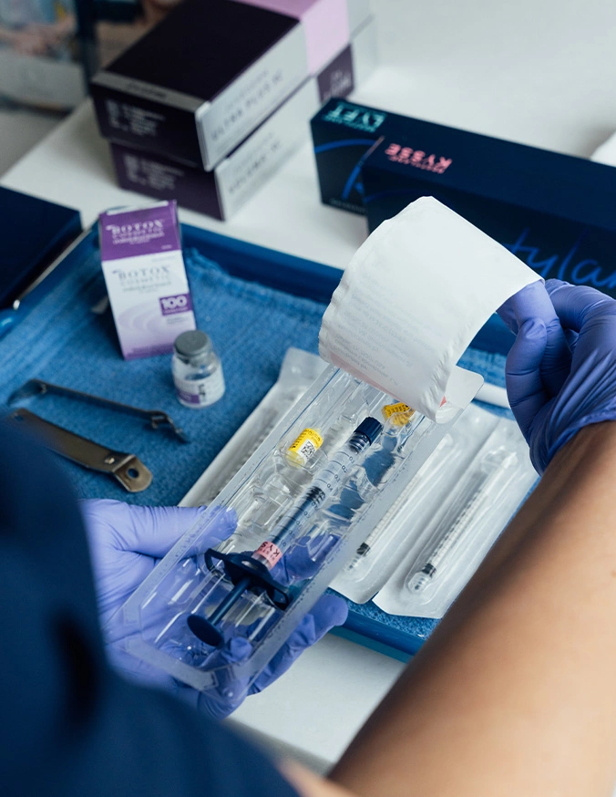 Medical supplies and sterile equipment laid out on blue surgical drape with gloved hands for clinical procedure - Dermal fillers in San Antonio, TX