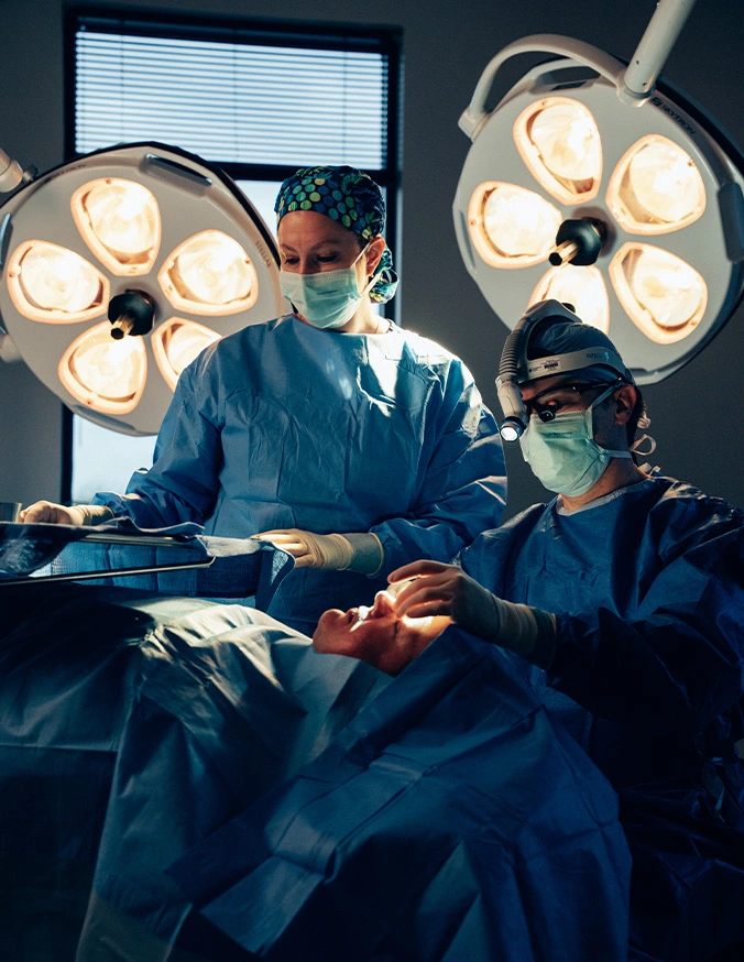 Dr Stallworth MD and Dr Rokosz performing operation in modern operating room with surgical lights overhead - Eyelid surgery in San Antonio, TX