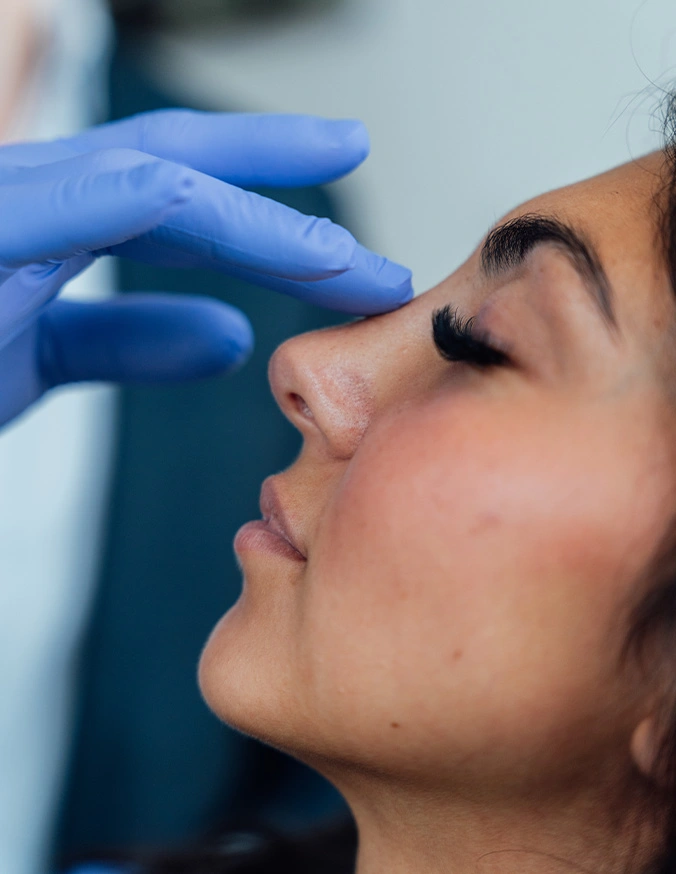 Medical professional examining patient's nose for cosmetic or rhinoplasty consultation procedure - Ethnic rhinoplasty in San Antonio, TX