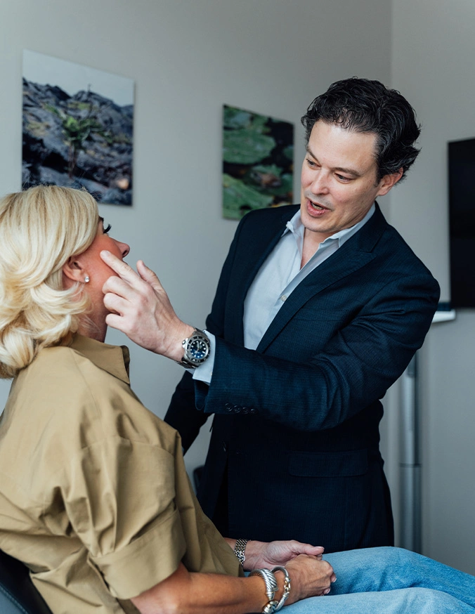 Dr Stallworth MD examining patient's face before cosmetic treatment in modern clinic - Facial fat grafting in San Antonio, TX