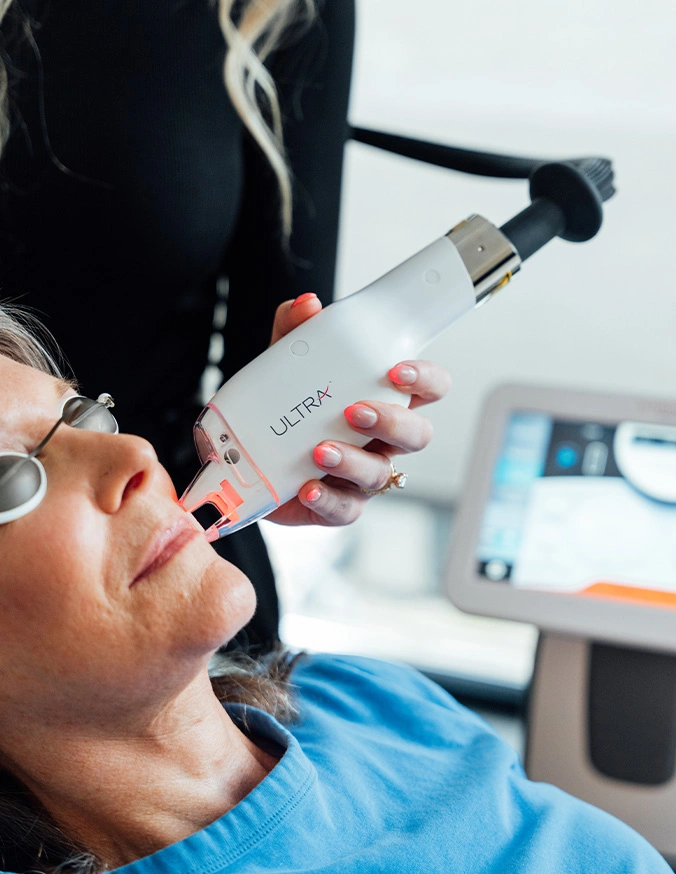 Doctor lasering patient's mouth during procedure in modern clinic office - Laser resurfacing in San Antonio, TX