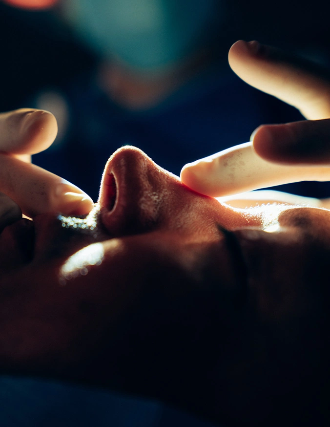 Close up shot of hands examining nose after surgery with contrasting lighting - Rhinoplasty in San Antonio, TX