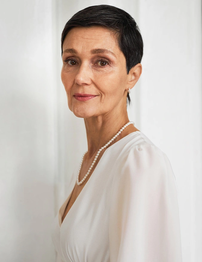 Elegant woman with short dark hair wearing white flowing blouse with gold necklace in professional portrait - Mohs reconstrucion in San Antonio, TX