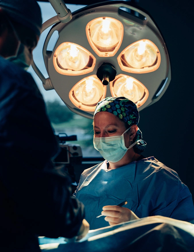 Dr Rokosz in blue scrubs and mask standing under surgical lights in operating room - Tummy tuck in San Antonio, TX